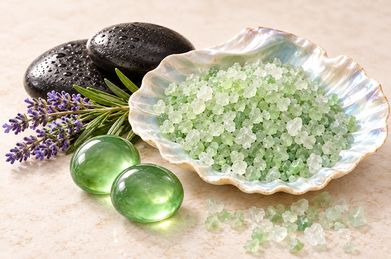 Warm black stones, lavender sprigs and green bath salts in a pearl shell
